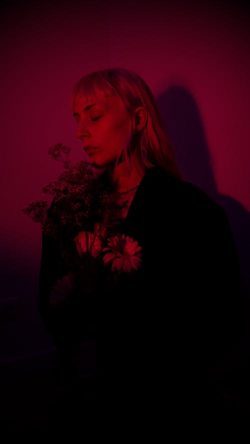 黑色西装外套站在红墙附近的女人 · 免费素材图片