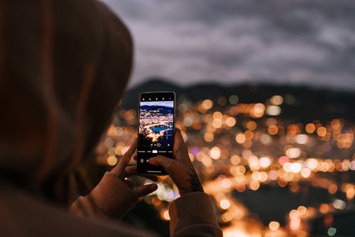 裁剪无法认出的人在智能手机上拍照的夜晚的城市 · 免费素材图片