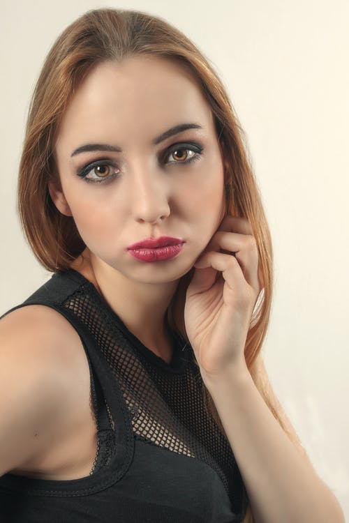 有关女人, 手放在脸颊, 摆姿势的免费素材图片