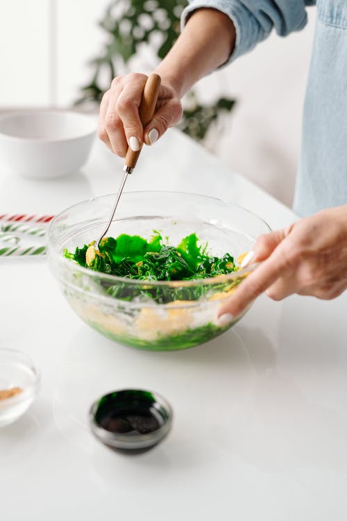 在碗里混合蔬菜沙拉的人 · 免费素材图片