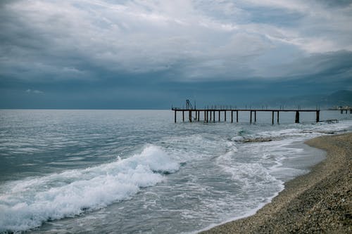 沙滩与码头附近的海浪 · 免费素材图片