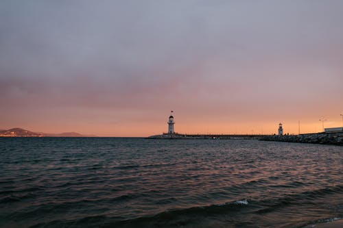 宁静的傍晚海边，与远程灯塔 · 免费素材图片