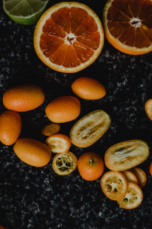 黑色大理石桌上切成薄片的橙色水果 · 免费素材图片