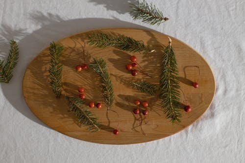 云杉分支放在木板上的冬青浆果附近 · 免费素材图片