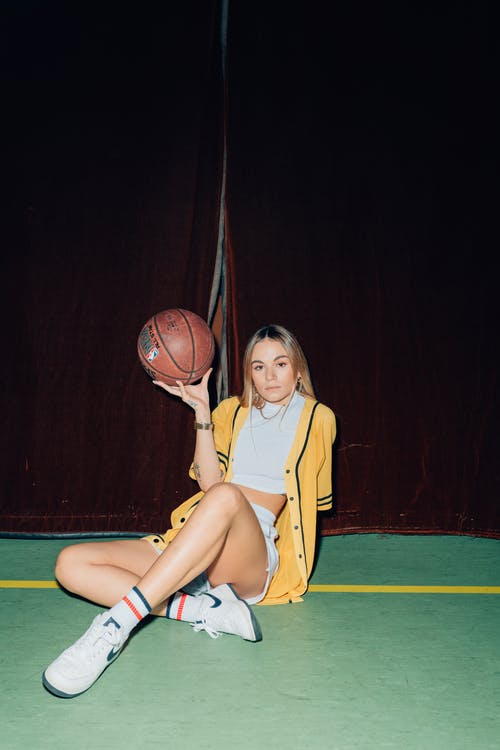 黄色衬衫坐在篮球场上的女人 · 免费素材图片
