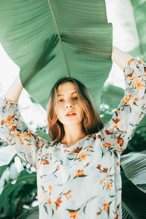 拿着绿叶的白色和红色花裙子的女人 · 免费素材图片