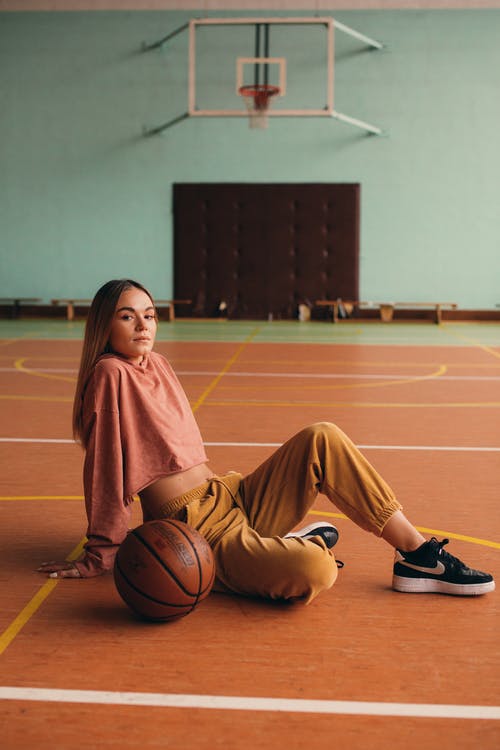 棕色长袍的女人坐在篮球场上 · 免费素材图片