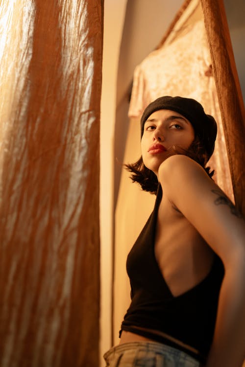 靠在棕色的窗帘的黑色背心的女人 · 免费素材图片