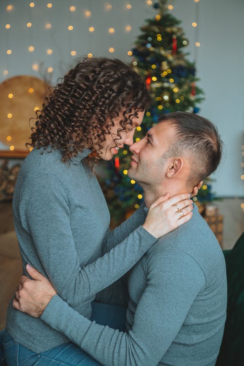 幸福的情侣拥抱在圣诞节装饰品的房间里 · 免费素材图片