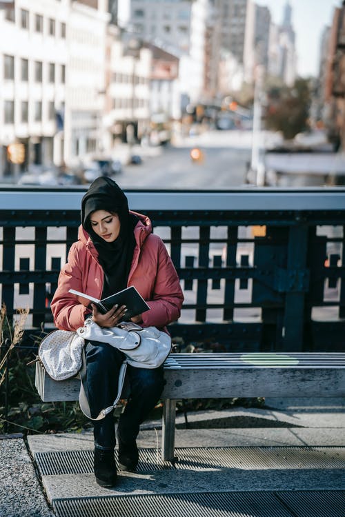 黑色的外套，坐在长椅上看书的女人 · 免费素材图片