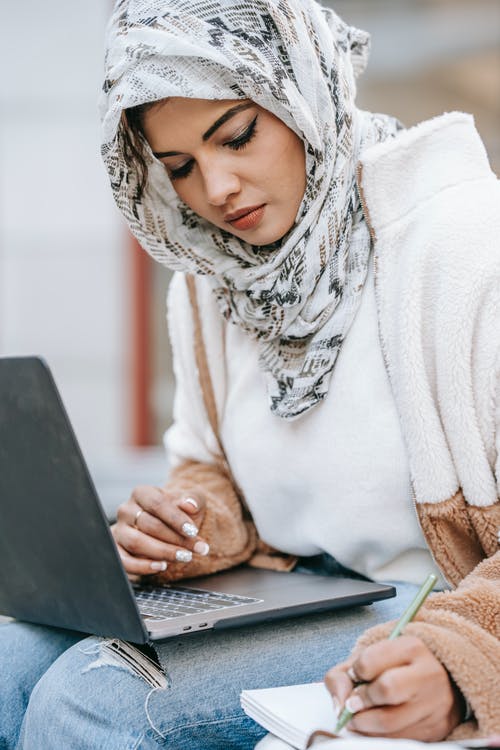 使用便携式计算机的白毛衣的女人 · 免费素材图片