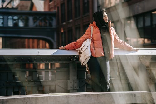 黑色的头巾和白大衣，站在灰色的混凝土墙旁边的女人 · 免费素材图片