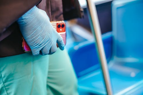 白衬衫和绿色的裤子，拿着橙色的智能手机的人 · 免费素材图片