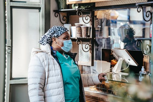白色和黑色的针织帽和蓝色夹克站在食品展示前的女人 · 免费素材图片