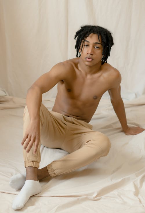 裸照的男人，穿着白色的裤子，坐在白色的床上 · 免费素材图片
