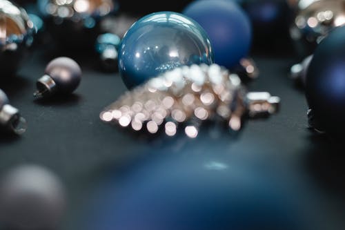 黑色桌上的银色和蓝色珠子 · 免费素材图片