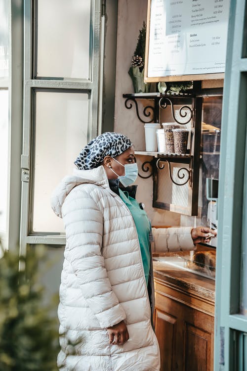站在玻璃窗口旁边的白色和黑色头巾的女人 · 免费素材图片