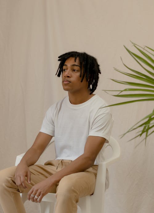 坐在白色的塑料扶手椅上的白船员的脖子t恤的女人 · 免费素材图片