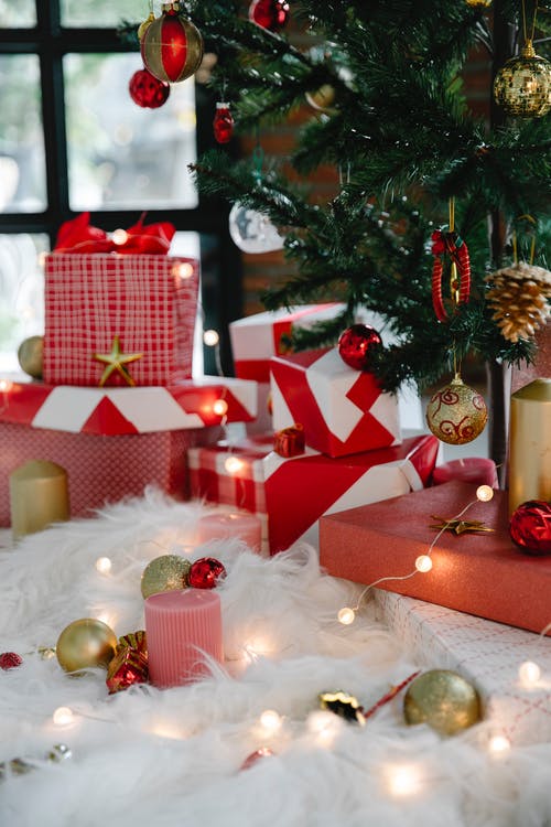 绿色圣诞树与小玩意旁边的红色和白色礼品盒 · 免费素材图片