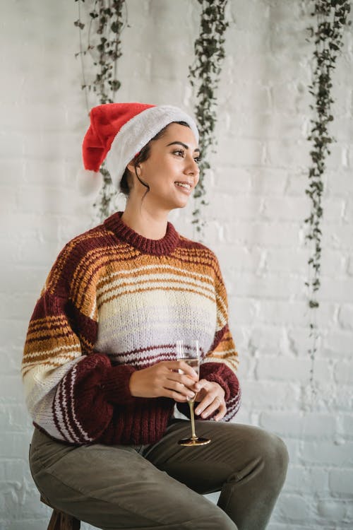 红色和白色的针织毛衫，戴着白色和红色的圣诞老人帽子的女人 · 免费素材图片