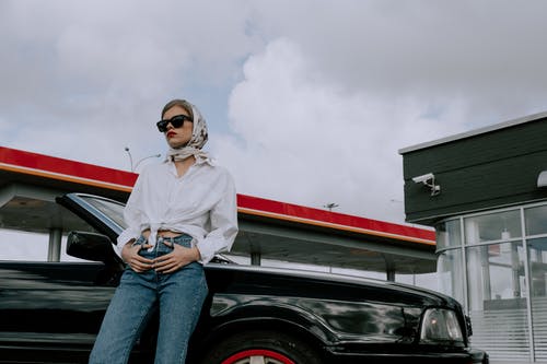 白色长袖衬衫和蓝色牛仔牛仔裤，坐在黑色的车上的女人 · 免费素材图片