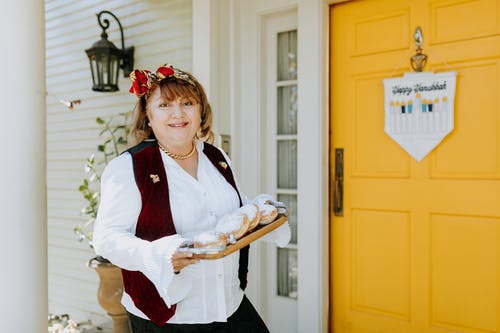 女人拿着一盘甜甜圈的照片 · 免费素材图片