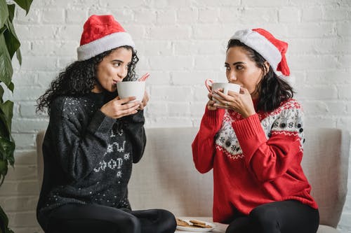 拿着白色陶瓷杯子的红色和白色编织帽的女人 · 免费素材图片