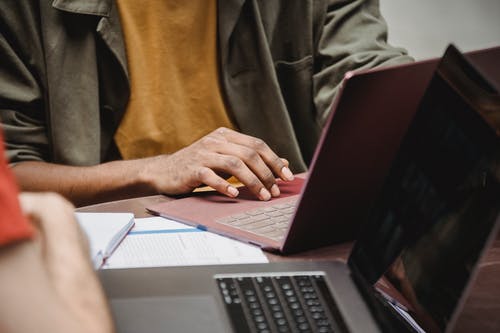 使用macbook Pro的棕色纽扣衬衫的人 · 免费素材图片