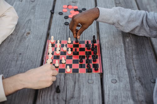 在灰色的木桌上玩象棋游戏的人 · 免费素材图片