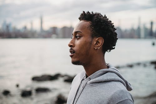 灰色连帽衫站在水体附近的人 · 免费素材图片