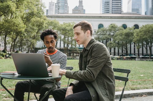 穿绿色外套的男人坐在椅子上，使用macbook · 免费素材图片