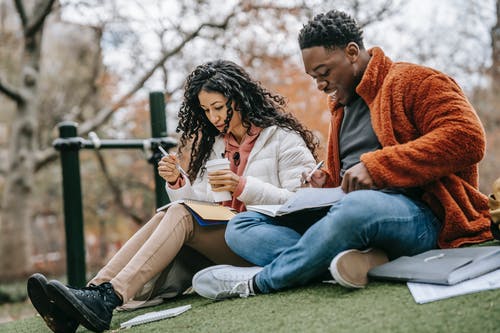 男人和女人坐在绿草地上 · 免费素材图片