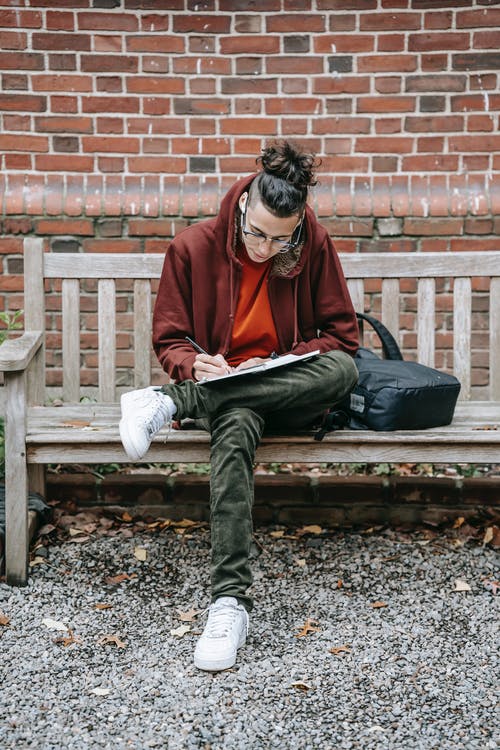 坐在棕色的木凳上的红色外套的男人 · 免费素材图片