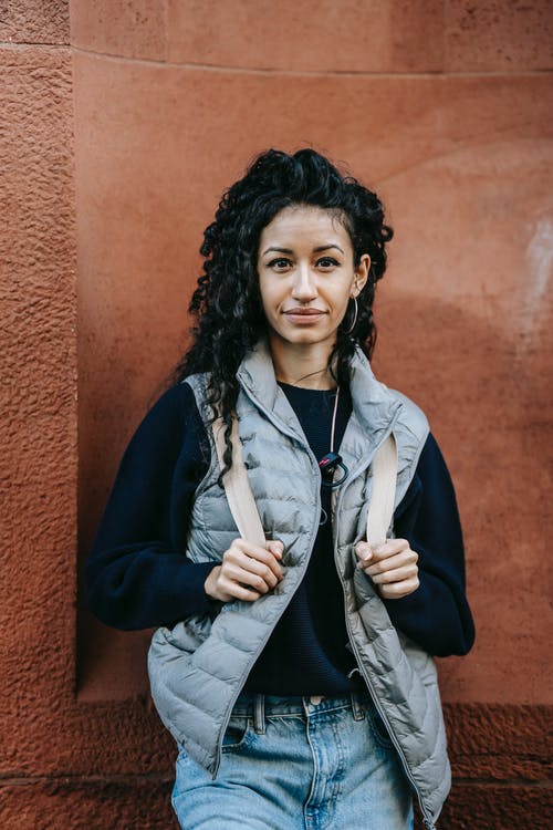 蓝色拉链夹克站在棕色墙旁边的女人 · 免费素材图片