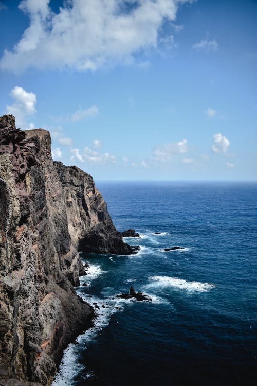 水体旁的棕色岩石地层 · 免费素材图片