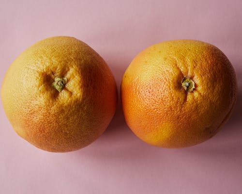 2粉红色表面上的橙色水果 · 免费素材图片