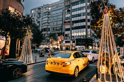 高层建筑附近道路上的黄色出租车 · 免费素材图片