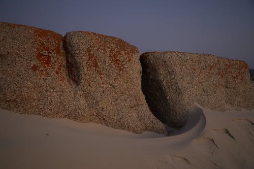 在白色沙滩上的棕色岩层 · 免费素材图片