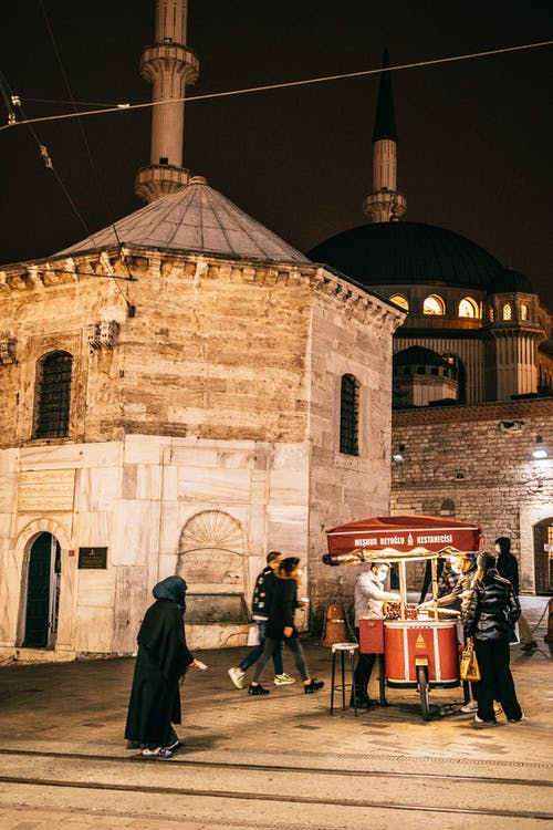 人们在夜间站在棕色混凝土建筑附近 · 免费素材图片