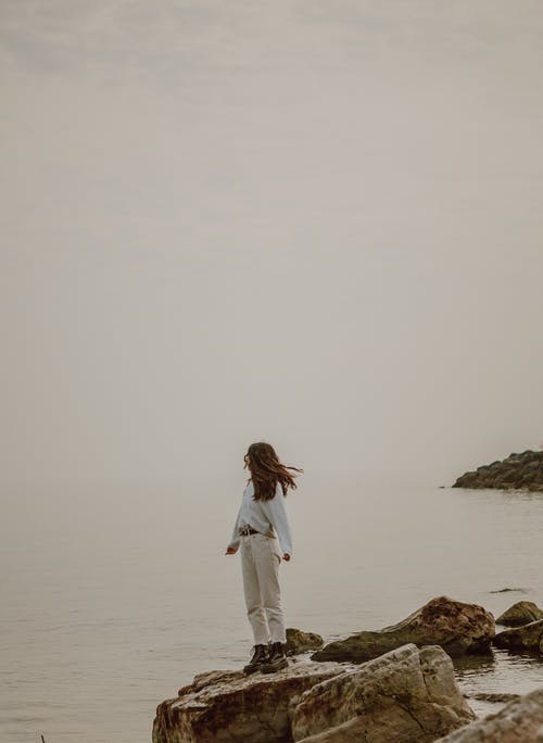 白色长袖衬衫和白色裤子站在棕色岩石附近的身体上的女人 · 免费素材图片