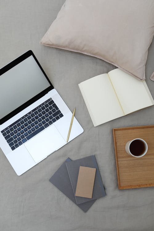 Macbook Pro旁边棕色木桌上的白色打印机纸 · 免费素材图片
