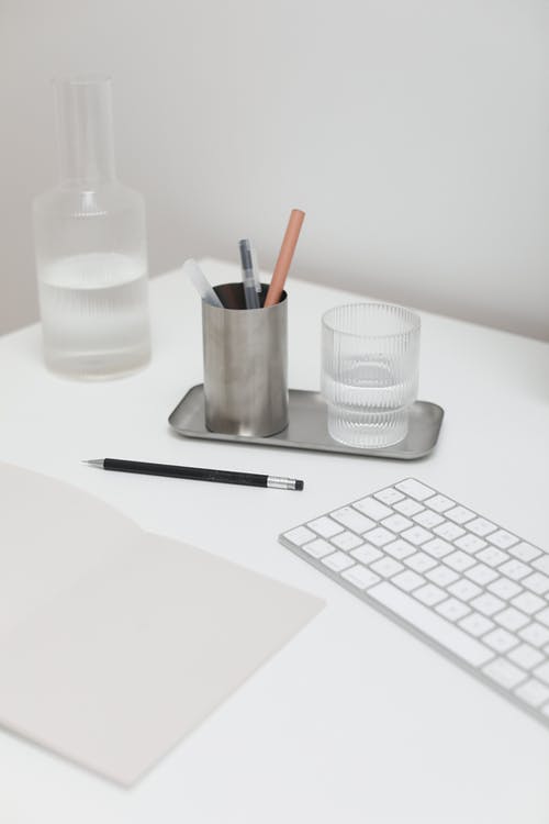 黑色笔旁边的白色塑料杯和白色桌上的白色塑料杯 · 免费素材图片