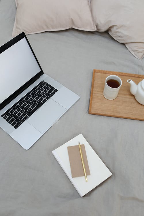 Macbook Pro旁边棕色木桌上的白色陶瓷杯 · 免费素材图片