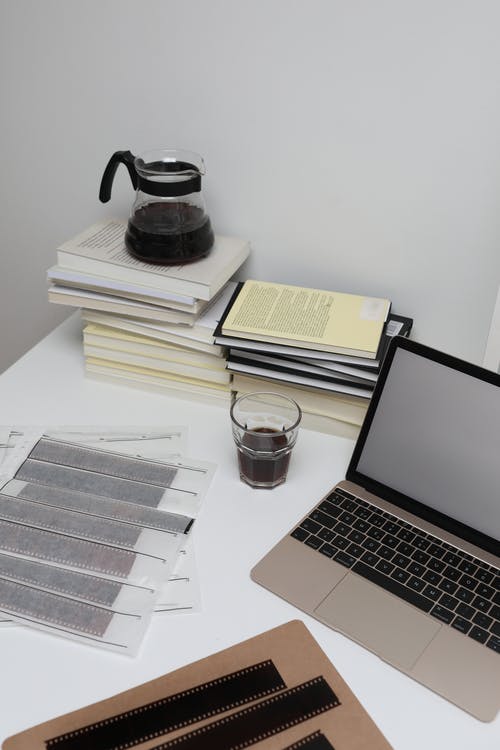 白色桌上的透明玻璃杯旁边的macbook Pro · 免费素材图片