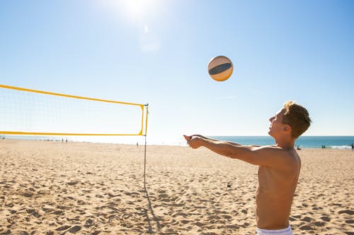 在沙滩上打排球的棕色短裤的男人 · 免费素材图片