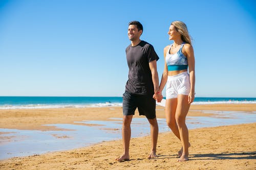 男人和女人站在海滩上 · 免费素材图片
