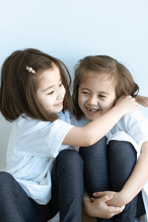 2个女孩坐在蓝色的沙发上 · 免费素材图片