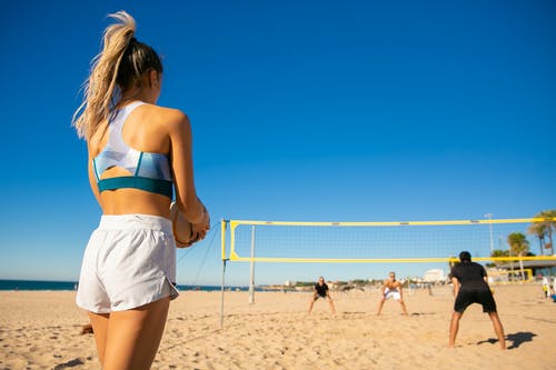 蓝色和白色的比基尼上衣和白色短裤，站在海滩上的女人 · 免费素材图片