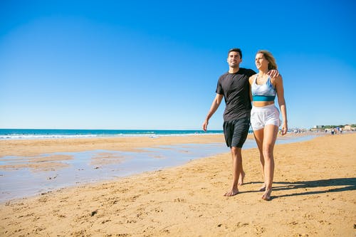 男人和女人在海滩上行走 · 免费素材图片