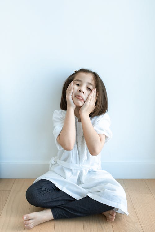 白色的长袖衬衫和蓝色牛仔牛仔裤，坐在棕色木地板上的女人 · 免费素材图片